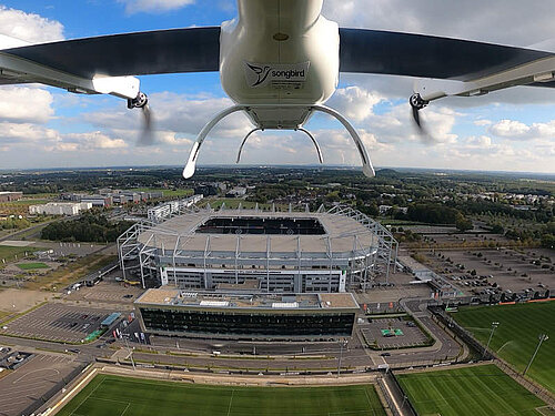 Songbird UAV im Flug mit Fu&szlig;ballstadion im Hintergrund